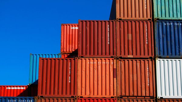 Stacked shipping containers against a bright blue sky