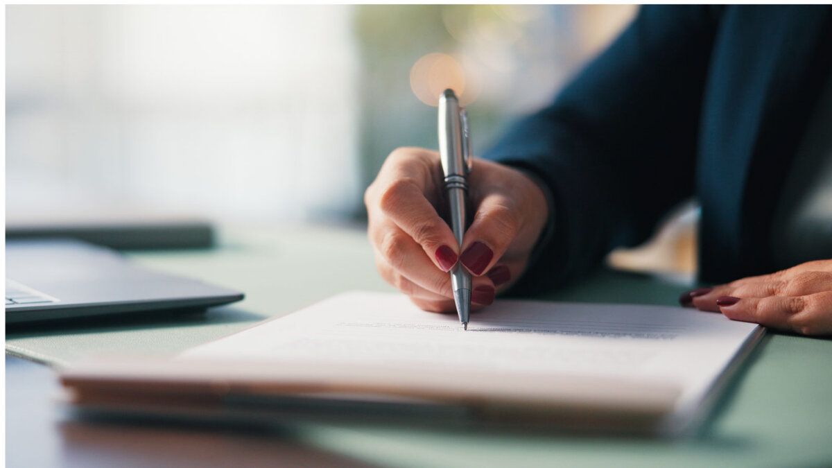 Woman signing a printed document with a pen at a desk