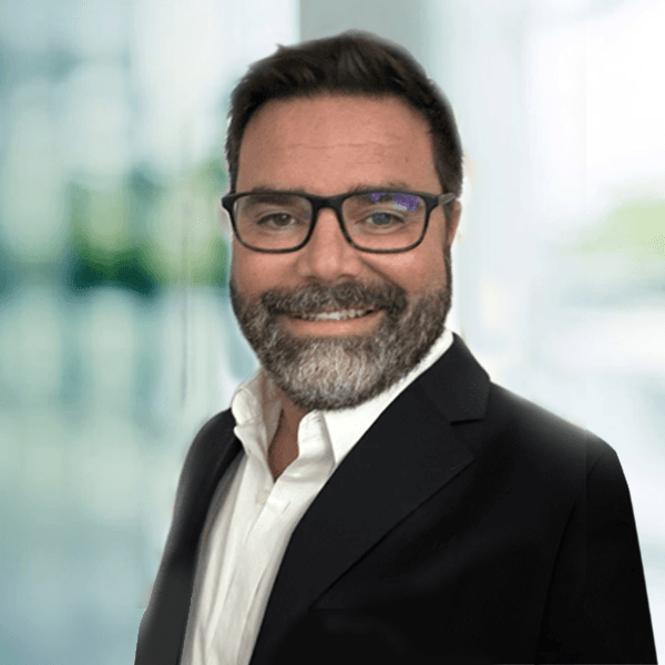 Smiling professional with salt-and-pepper beard and black glasses in business portrait